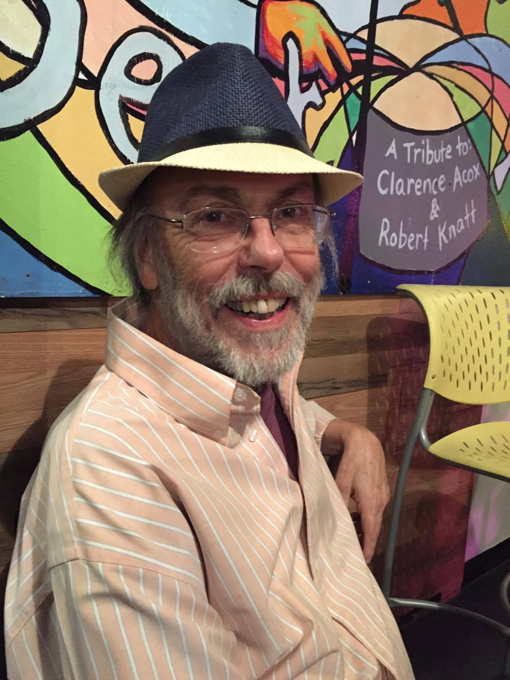 man smiling hat sitting collared shirt