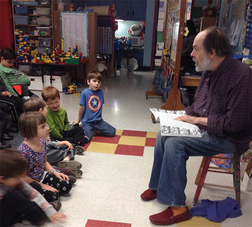 man seated beard telling stories children listening classroom